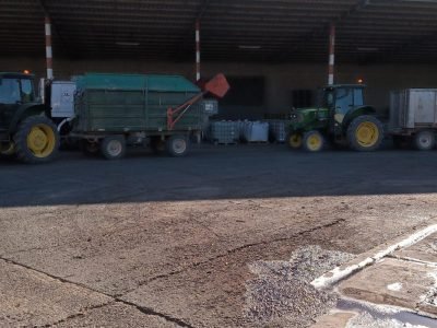 Tractores John Deere verdes con remolques realizando trabajos de agricultura sostenible en nave agrícola